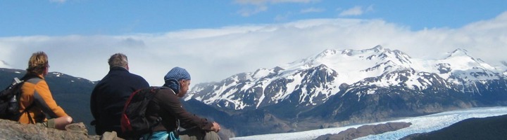Wandelaars kijken uit over een gletsjer en besneeuwde bergen in Patagonië tijdens een rondreis.