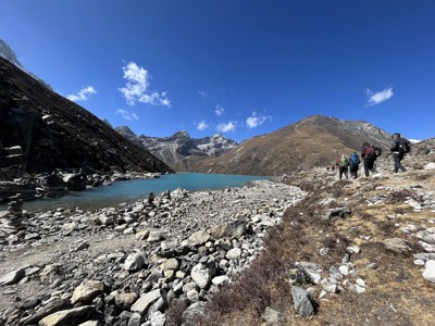 Wandelaars langs een turquoise bergmeer op de Everest Base Camp-route in Nepal.