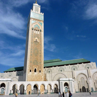 Hassan II-moskee in Casablanca, Marokko, met hoge minaret en witte bogen onder een blauwe lucht.
