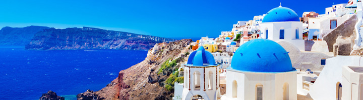 Witblauwe koepelkerken en huizen op de kliffen van Santorini aan zee, Griekenland.