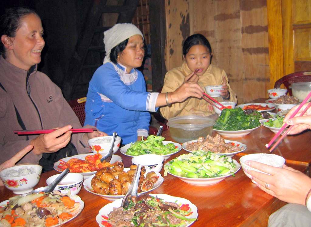 Samen eten met een Vietnamese familie tijdens een groepsrondreis Vietnam, met lokale gerechten op tafel.
