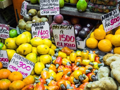 Fruitkraam op lokale markt in Costa Rica met mango’s, citrus en cashewnoten met prijsbordjes.