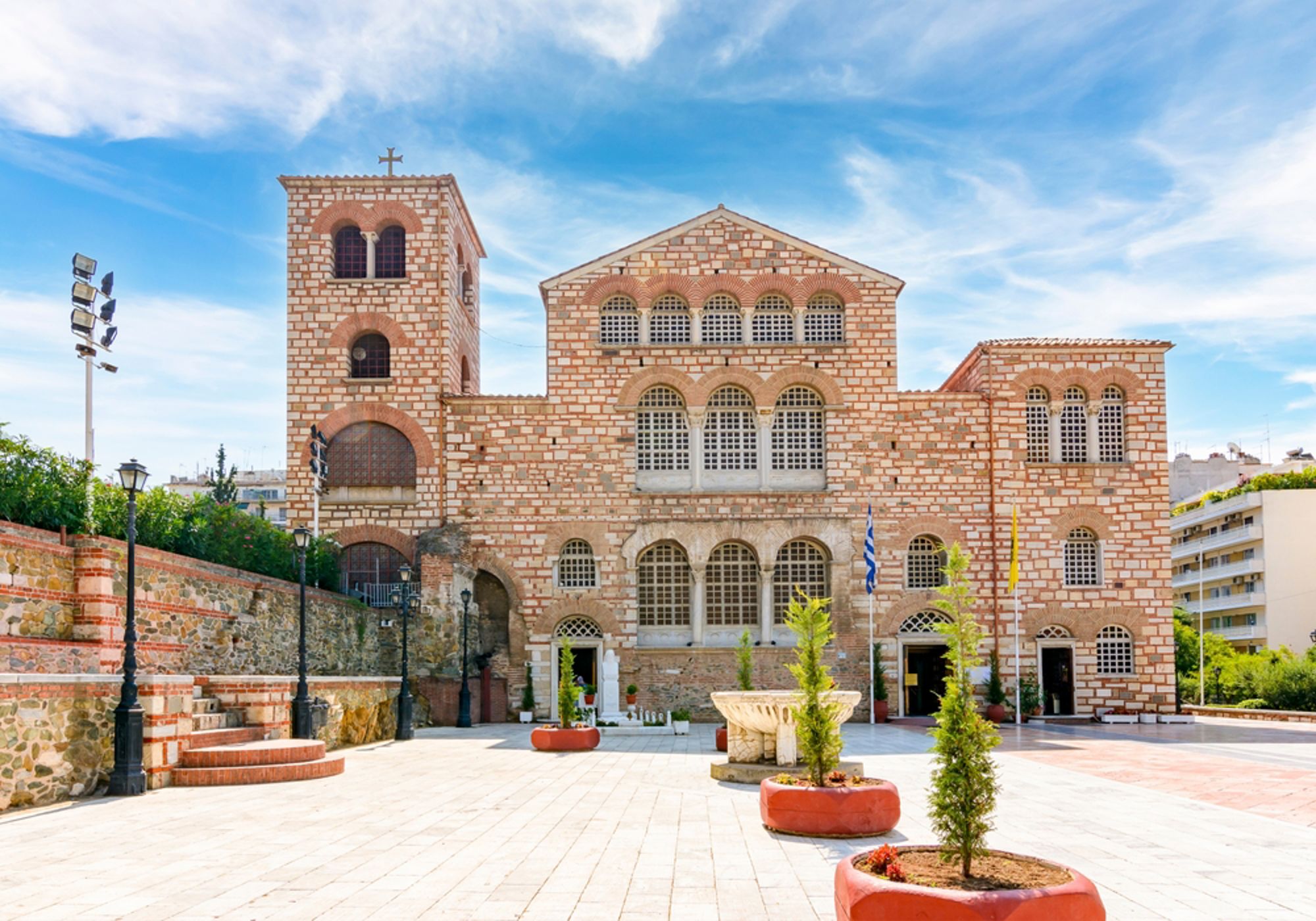 Gevel van de Agios Dimitrios-kerk in Thessaloniki, Griekenland, met plein en Griekse vlaggen.