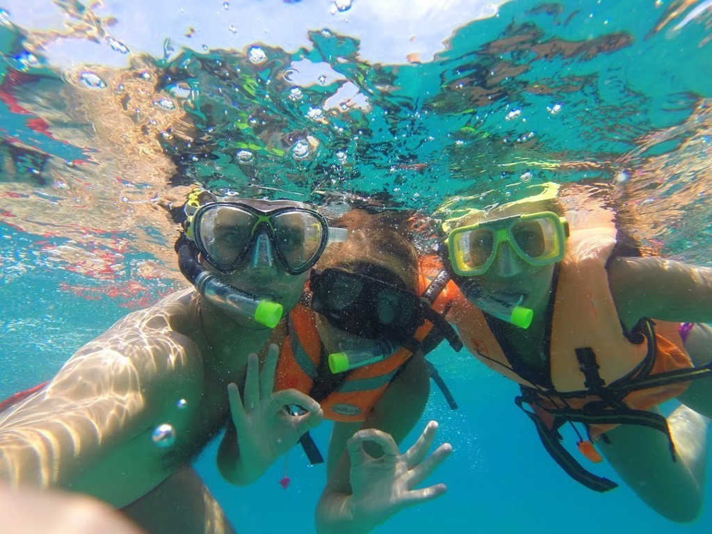 Gezin snorkelt in helderblauw water tijdens familiereis Maleisië.