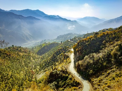 Slingerweg door groene bergen met mistige valleien langs de Route Spiti & Ladakh.