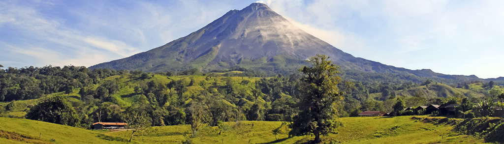 Vulkaan Arenal in Costa Rica met groene heuvels en regenwoud op de voorgrond.