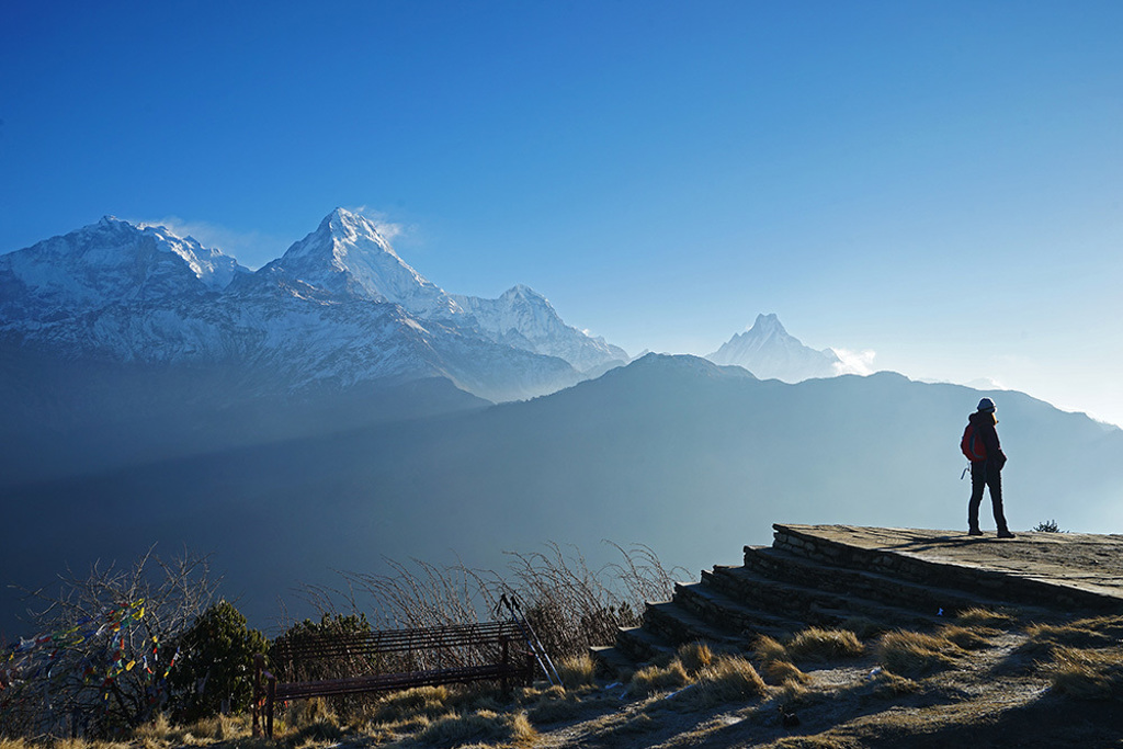 Wandelaar met rugzak kijkt uit over de besneeuwde Himalaya bij de Annapurna Basecamp-trektocht in Nepal.