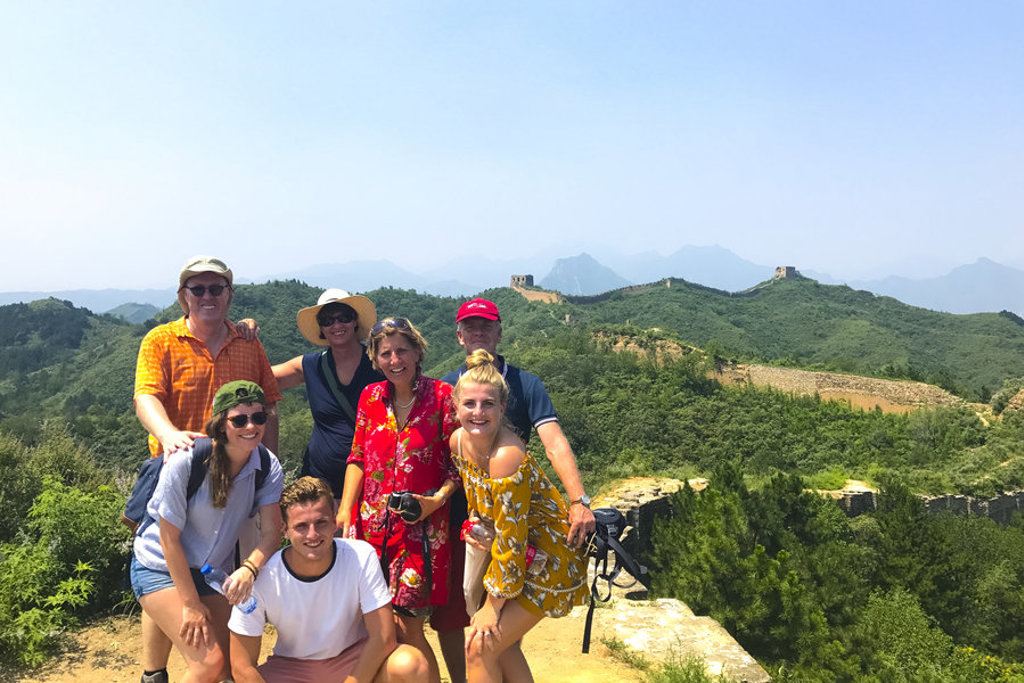 Reizigers op de Chinese Muur tijdens een groepsrondreis China, met uitzicht op groene bergen.