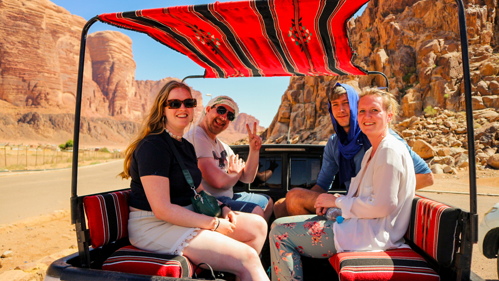 Jonge reizigers in een pick-up met rood tentdoek tijdens een 22-35ers reis door Jordanië.