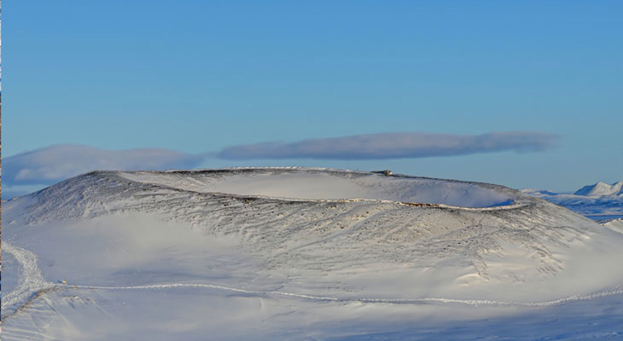Besneeuwd vulkaanlandschap in IJsland onder een heldere blauwe lucht.