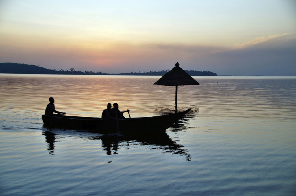 Vissers in een kano op het Victoriameer bij zonsondergang tijdens een groepsrondreis Oeganda.