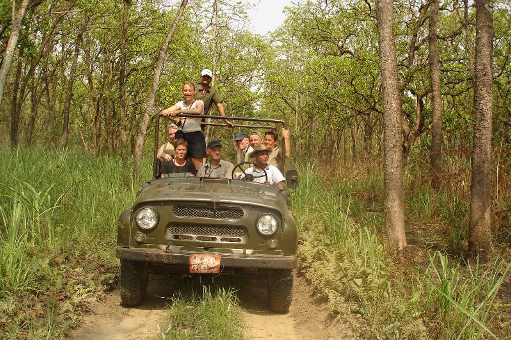Groep reizigers in open jeep op onverharde weg door bos in Nepal tijdens groepsrondreis Annapurna Basecamp.