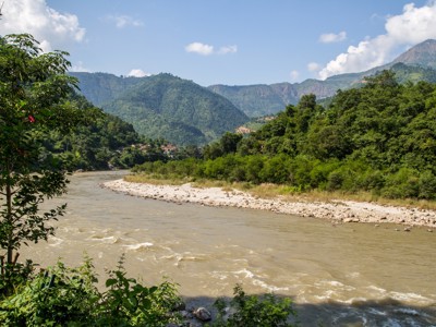 Rivier in groene vallei met bergen op de achtergrond langs de Route Nepal.