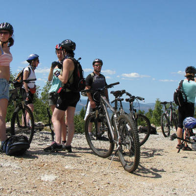 22-35ers op mountainbikes tijdens een groepsreis door de Balkan, met uitzicht op bergen onder een blauwe lucht.