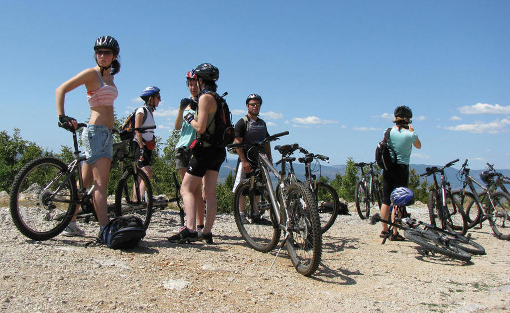22-35ers op mountainbikes tijdens een groepsreis door de Balkan, met uitzicht op bergen onder een blauwe lucht.