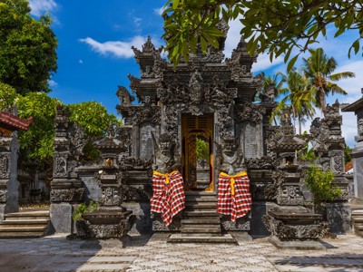 Balinese tempelpoort met gedetailleerde steenornamenten en rood-wit geblokte doeken, tijdens Route Java en Bali.