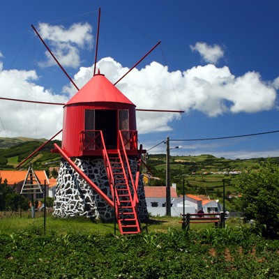 Rode windmolen in groen heuvellandschap op de Azoren tijdens de Groepsrondreis Azoren Compleet.