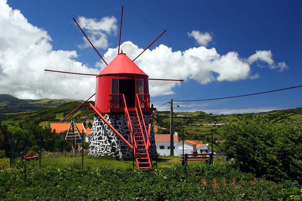 Rode windmolen in groen heuvellandschap op de Azoren tijdens de Groepsrondreis Azoren Compleet.