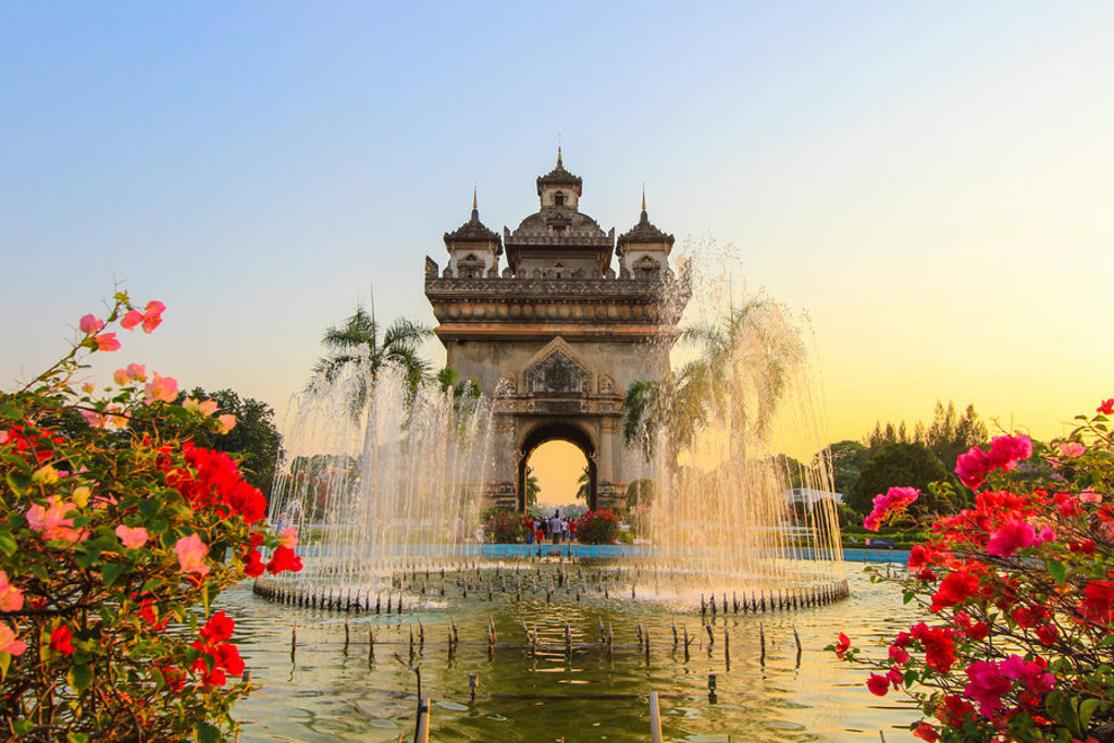Patuxai-monument in Vientiane, Laos, met fonteinen en bloemen bij zonsondergang tijdens familiereis Thailand, Laos en Cambodja.