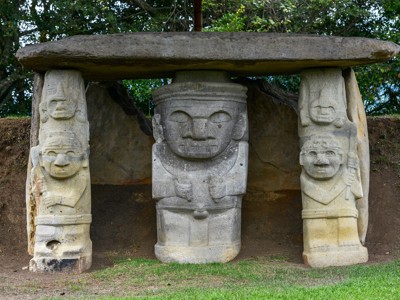 San Agustín archeologisch park in Colombia met stenen beelden onder een grote deksteen.