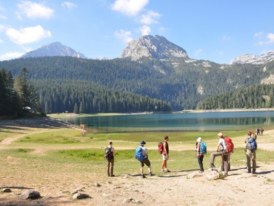 Wandelaars bij het Zwarte Meer in Durmitor Nationaal Park, Montenegro, met berglandschap op de achtergrond.
