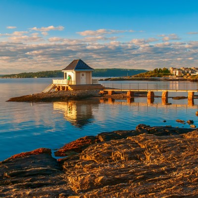 Steiger naar een klein paviljoen aan een rustige kust in Scandinavië bij zonsondergang.