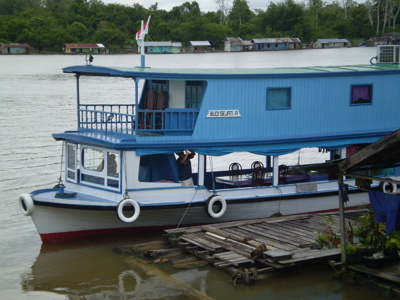 Blauwe rivierboot bij een houten steiger op de rivier in Kalimantan, Route Kalimantan.