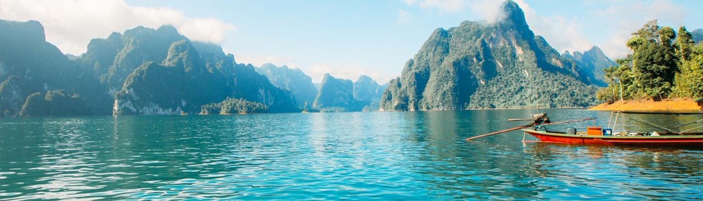 Longtailboot op helder meer met kalksteenbergen in Thailand, familiereis Noord en Zuid.