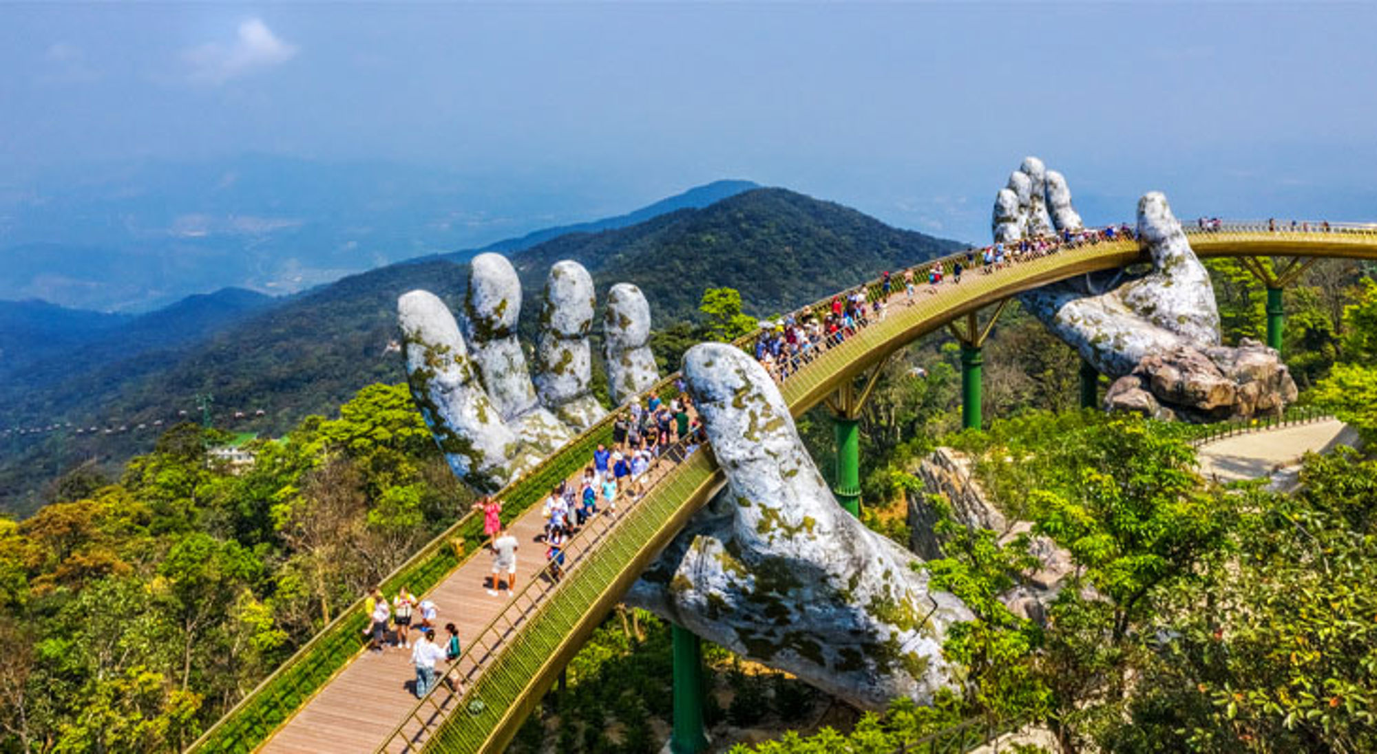 Gouden Brug (Golden Bridge) in Ba Na Hills, Da Nang, Vietnam, gedragen door reuzenhanden boven het berglandschap.