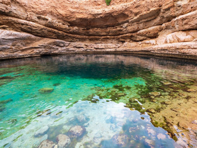 Helderblauwe waterpoel in een rotsachtige wadi in Oman, route Oman en Dubai.