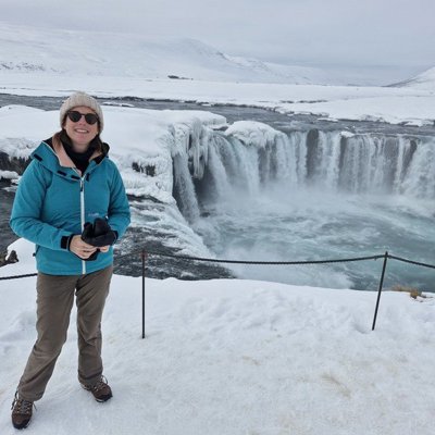 Reiziger in winterkleding bij een besneeuwde waterval in Noord-IJsland tijdens een groepsrondreis.
