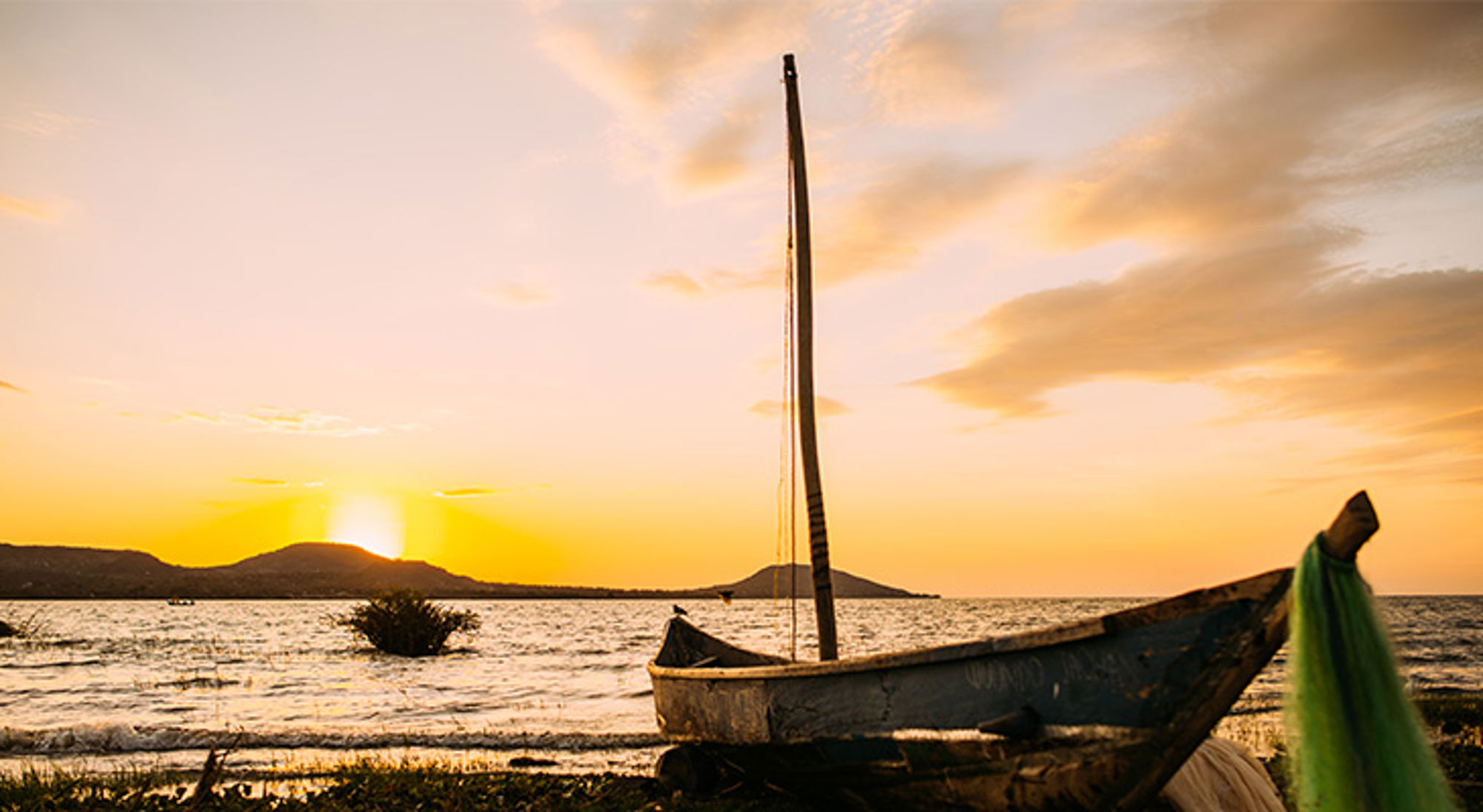 Houten dhow-boot aan de oever bij zonsondergang in Tanzania.