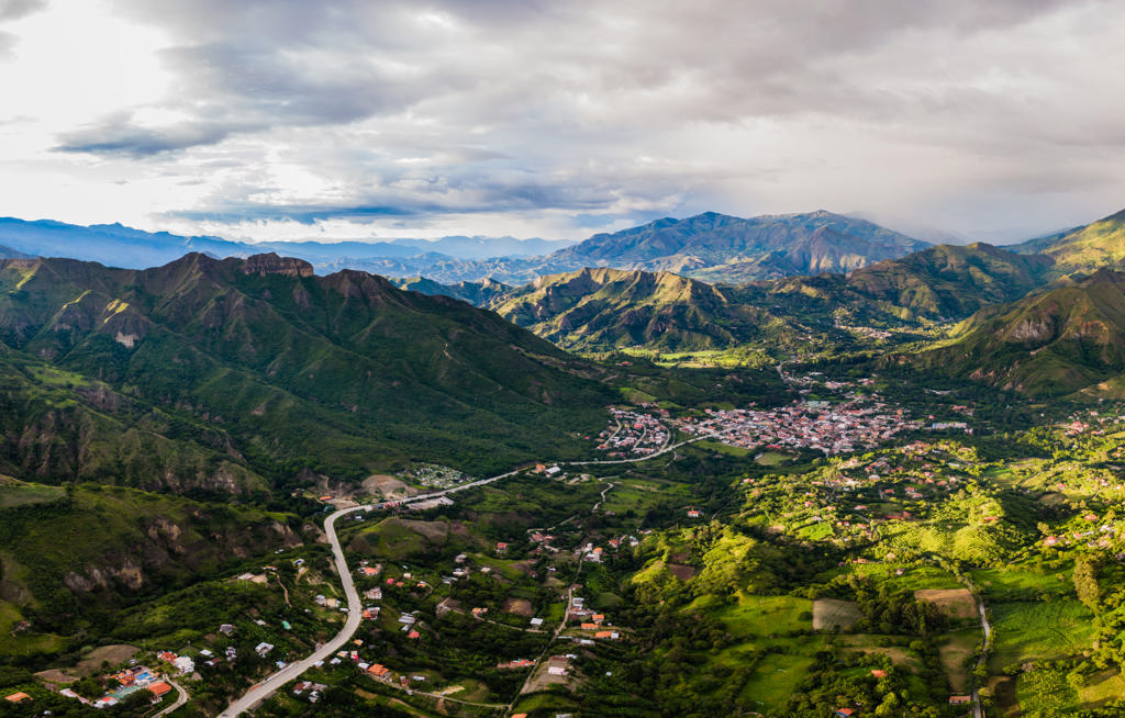 Panoramisch uitzicht op groene Andesvallei met dorp en slingerende weg in Ecuador.