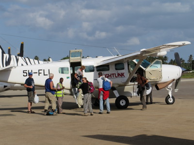 Reizigers stappen in een klein propellervliegtuig op de landingsbaan tijdens de route Kenia, Tanzania en Zanzibar.