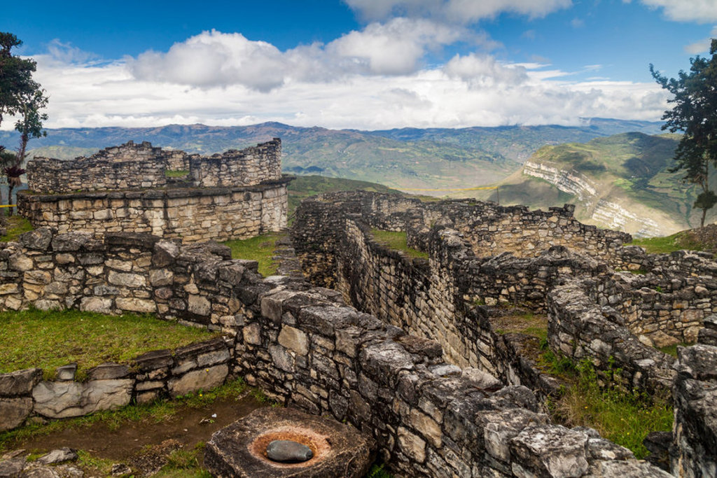 Kuelap-ruïnes in Noord-Peru met stenen muren en uitzicht op de Andes onder een blauwe lucht.