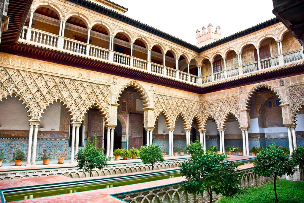 Binnenplaats van het Real Alcázar in Sevilla met Moorse bogen, tegelwerk en waterpartij.