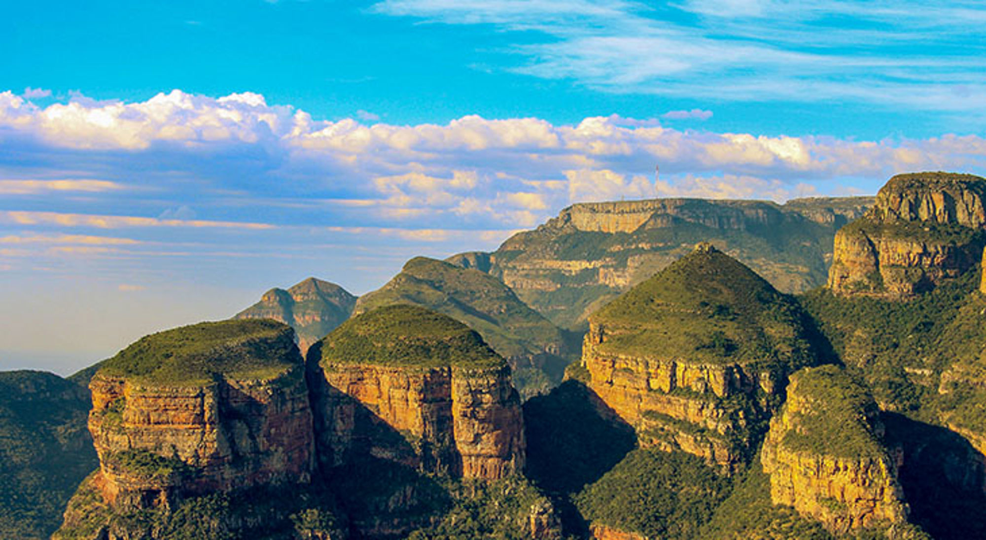 Three Rondavels bij Panorama Route Uitzicht op de Blyde River Canyon met groene rotsformaties onder een blauwe lucht, Zuid-Afrika.