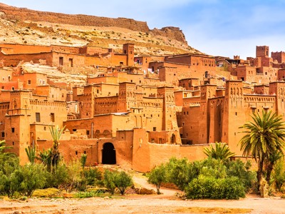 Kasbah Aït Ben Haddou langs de Route Marokko, met lemen huizen en palmbomen tegen de heuvels.
