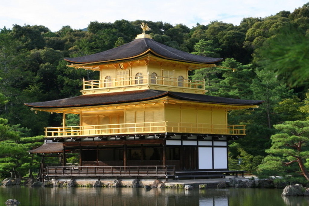 Gouden Paviljoen Kinkaku-ji in Kyoto, Japan, aan een vijver met groene bomen op de achtergrond.