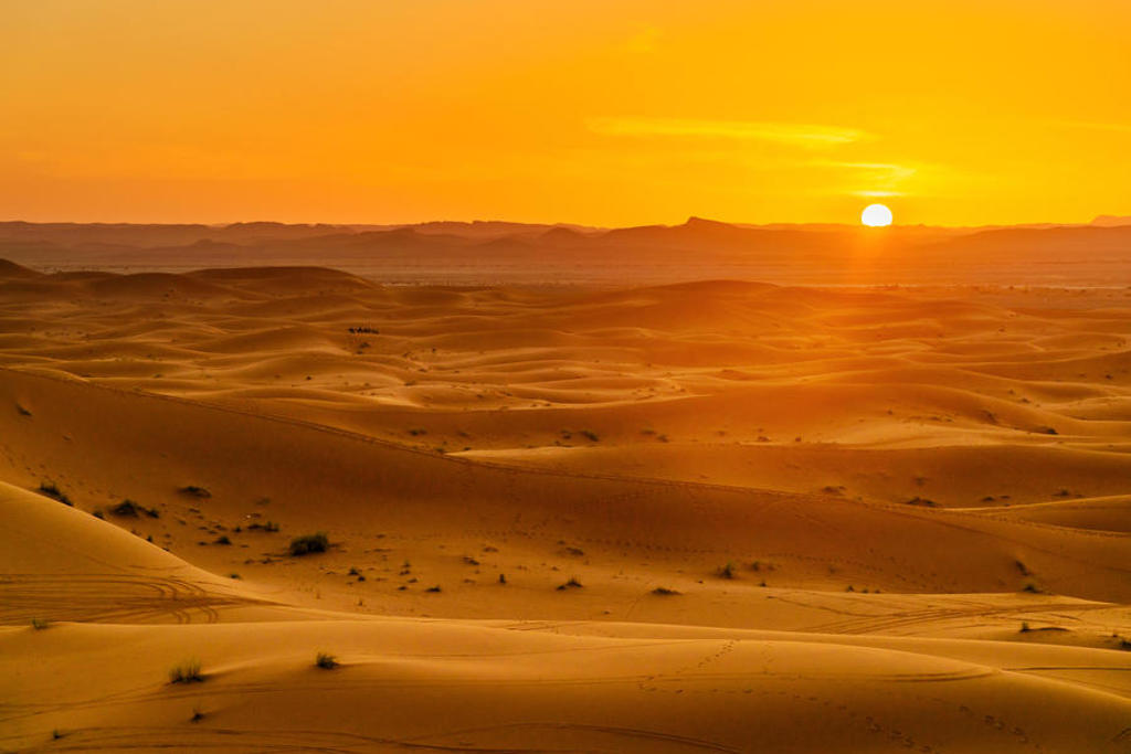Zonsondergang boven zandduinen in de Sahara tijdens de premium groepsrondreis door Marokko.