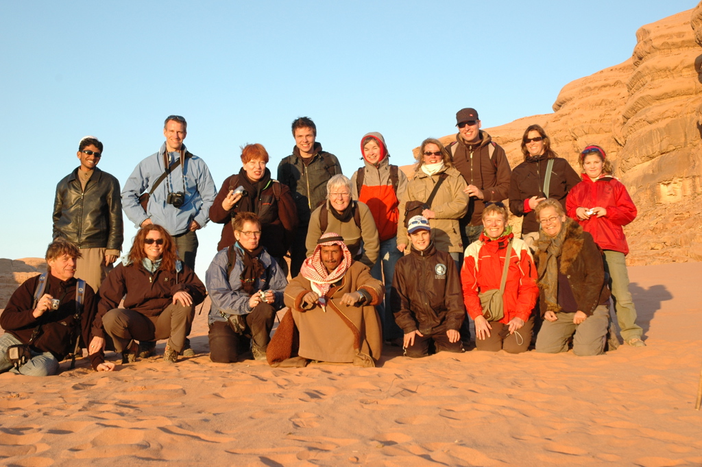 Groepsfoto van reizigers tijdens een groepsrondreis Jordanië, in de woestijn bij rotsformaties.