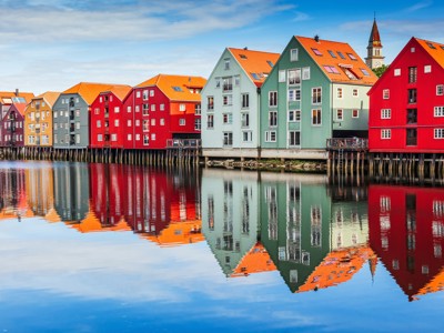 Kleurrijke pakhuizen aan de kade in Trondheim, Noorwegen, met spiegeling in het water.