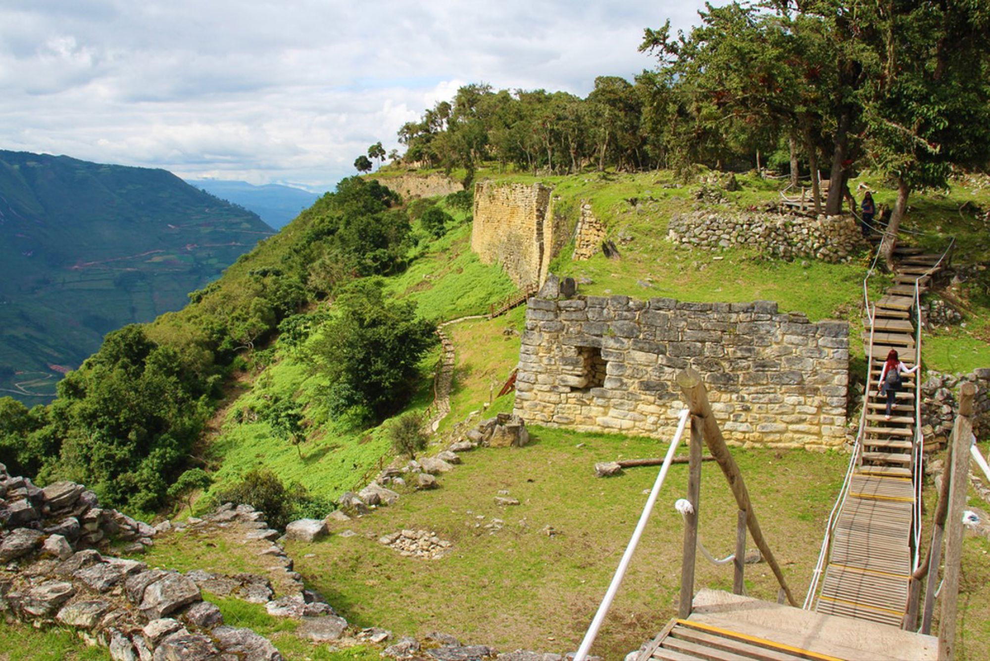 Ruïnes van het fort Kuelap met houten loopbrug en uitzicht over de groene vallei in Peru.