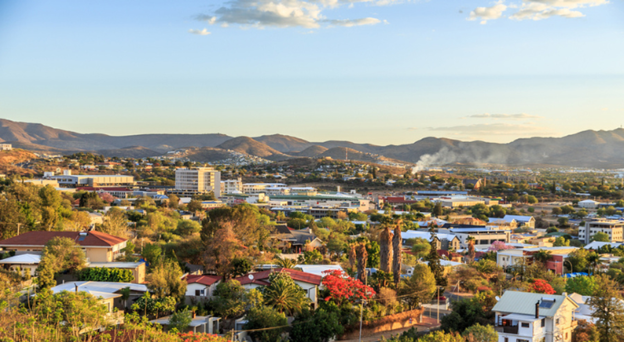 Panorama van Windhoek, Namibië, met stadscentrum en omliggende bergen bij zonsondergang.