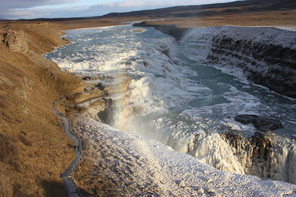 Waterval in een brede canyon met bevroren randen in IJsland tijdens een groepsrondreis.