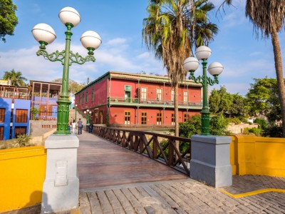 Houten brug met groene lantaarns en kleurrijke gebouwen in Barranco, Lima, op de Route Noord-Peru.