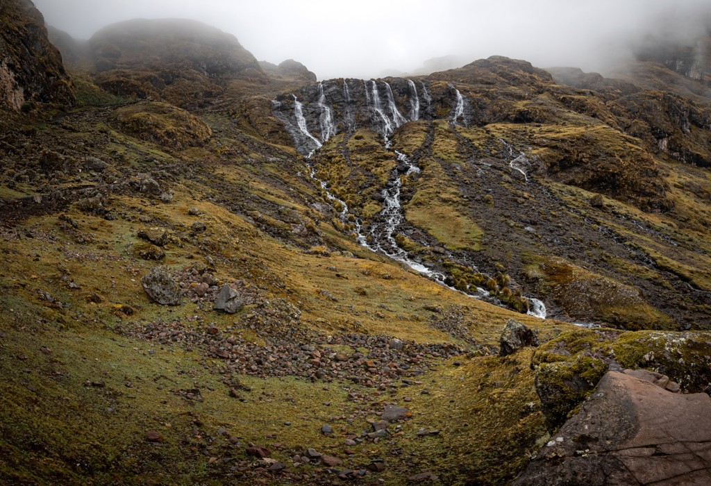 Watervallen in het Andesgebergte in Peru, omringd door ruige berghellingen en mist.