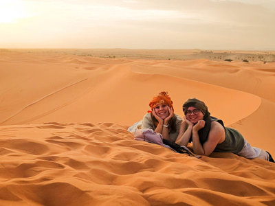 Reizigers liggen op zandduinen in de Sahara tijdens de route door Marokko.