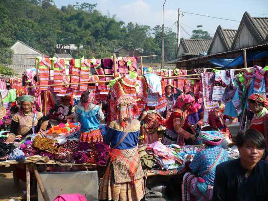 Markt in Vietnam met kleurrijke klederdracht en textielkramen tijdens een groepsrondreis door Vietnam.