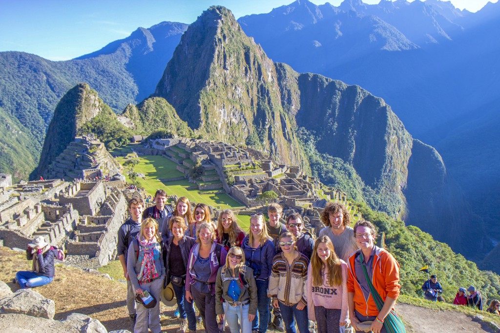 Groep reizigers bij Machu Picchu met uitzicht op de Inca-ruïnes en de bergen van Peru.